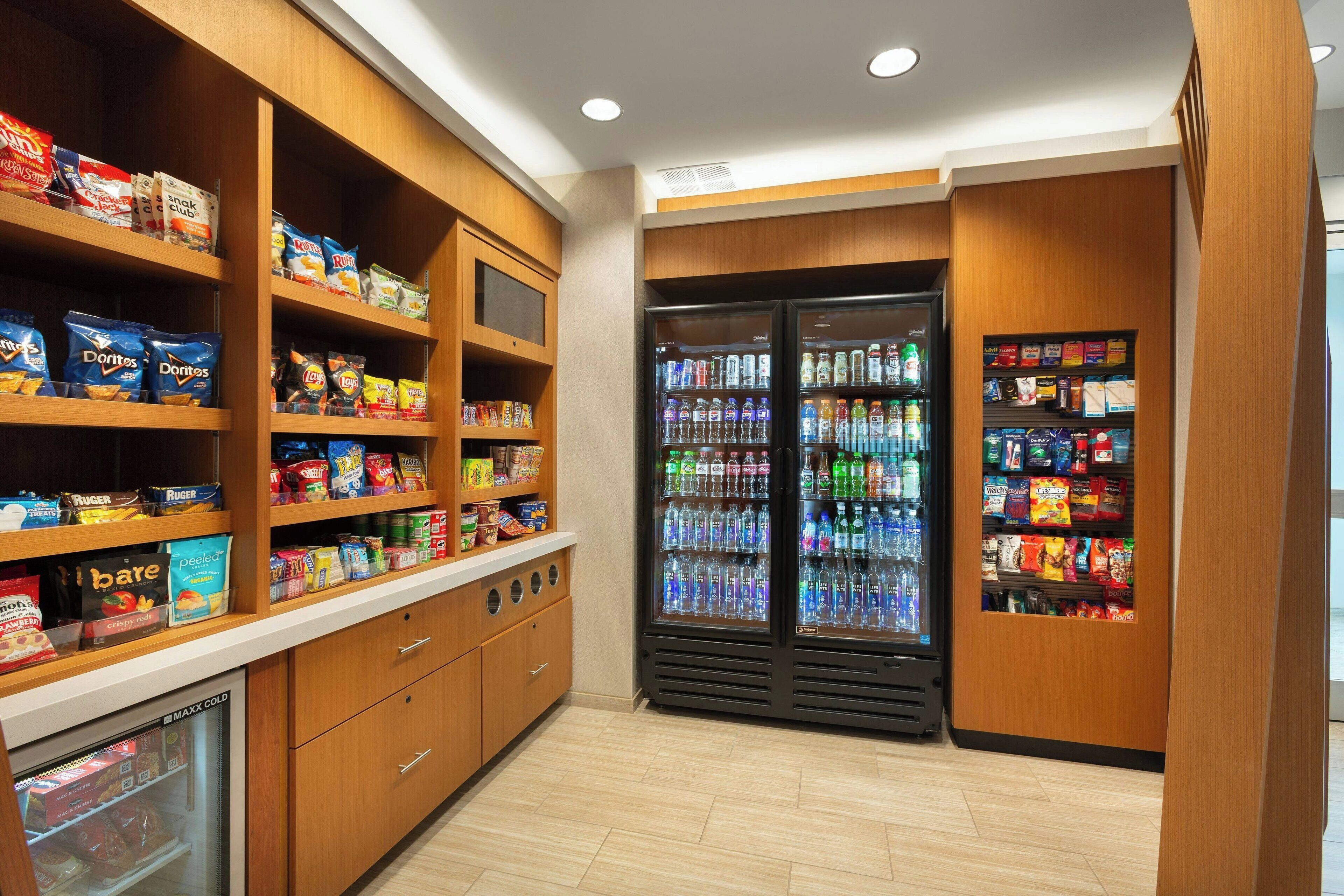 A snack and beverage area with shelves stocked with various snacks and a refrigerated section with bottled drinks.