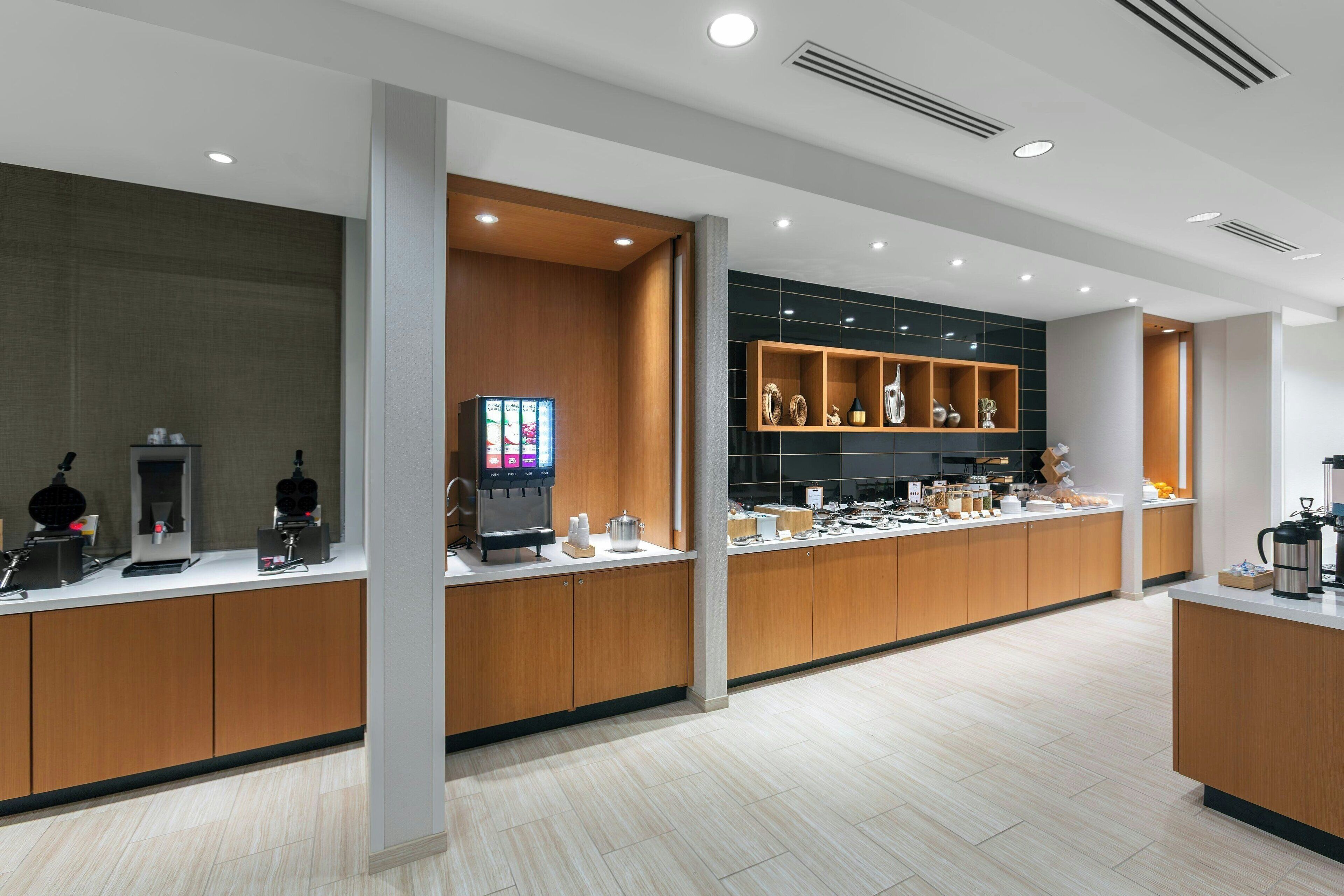 A modern hotel lobby with wooden reception counters, a coffee station, and a display of decorative items.