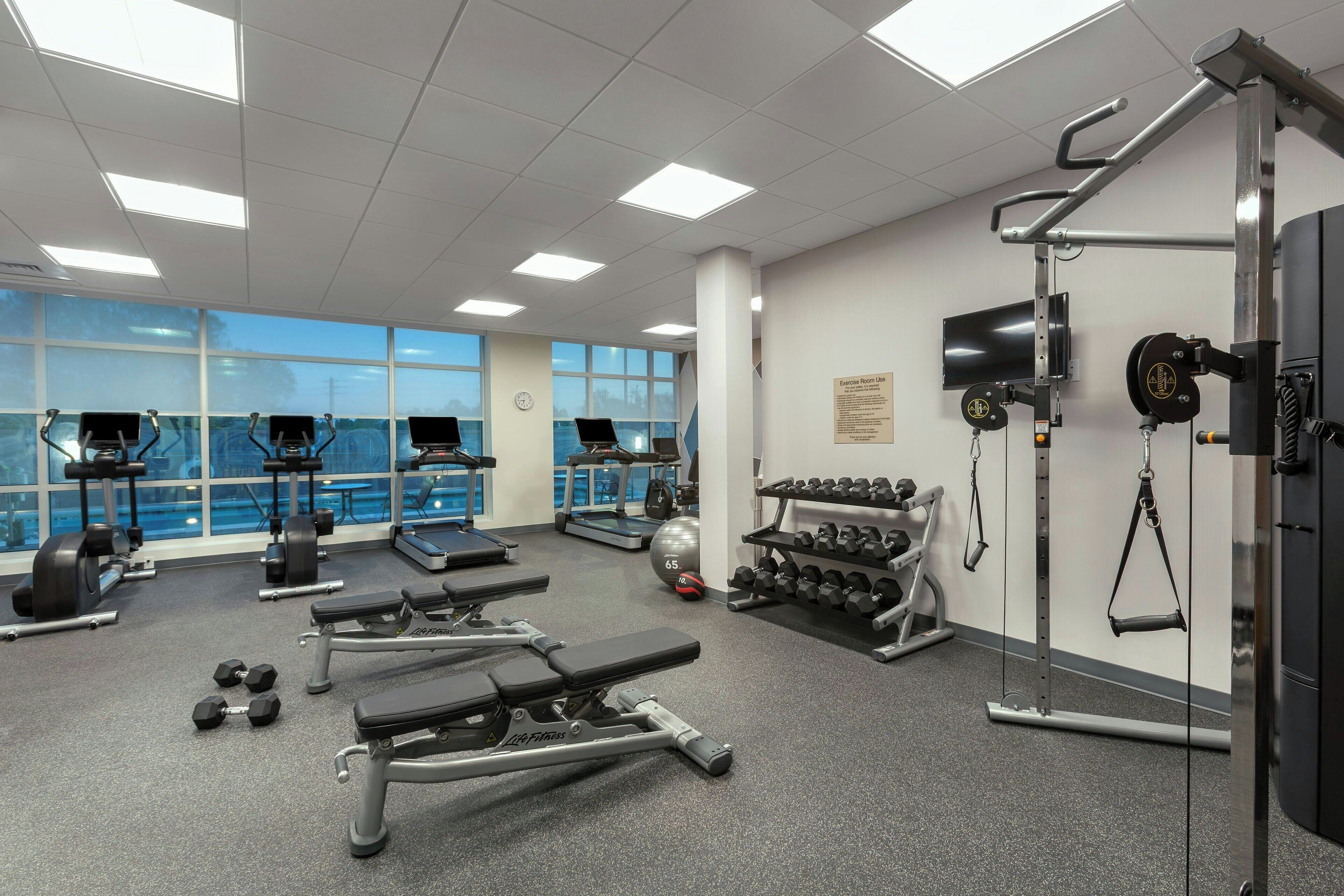 Une salle de sport équipée de matériel d’exercice, de tapis de course et d’haltères.