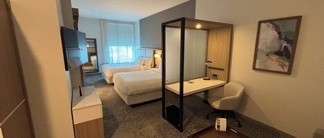 A hotel room with a bed, desk, chair, and a TV.