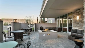 An outdoor patio with stone flooring, wicker furniture, a fire feature, and a stone accent wall.