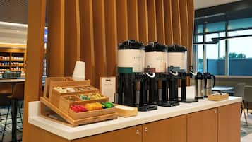 A coffee station with multiple coffee makers and a tray of assorted pastries.