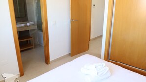 A hotel room with a bed, a wooden door, a bathroom with a sink, and a towel on the bed.