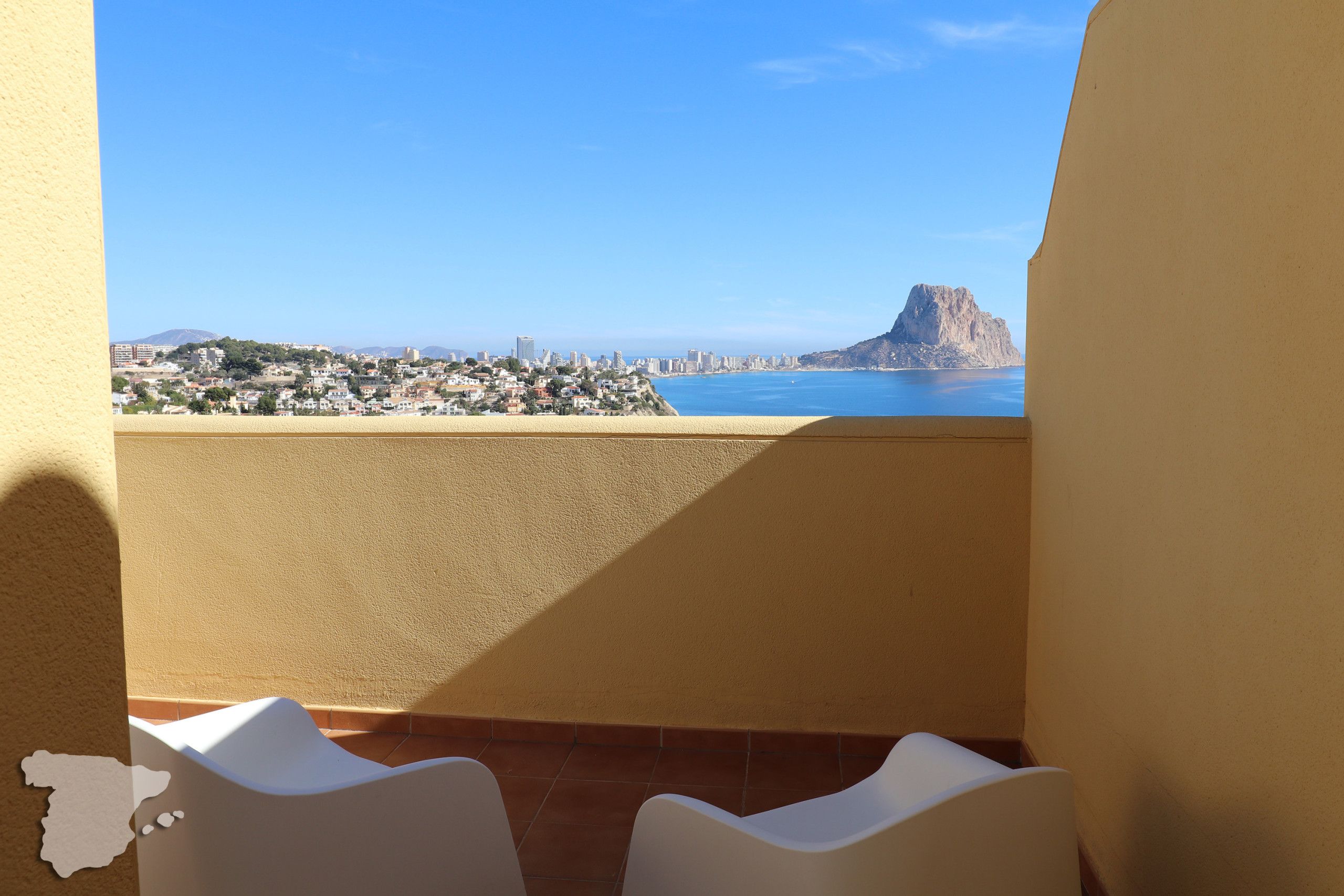 A balcony with a view of a coastal cityscape, including a prominent mountain and a body of water.