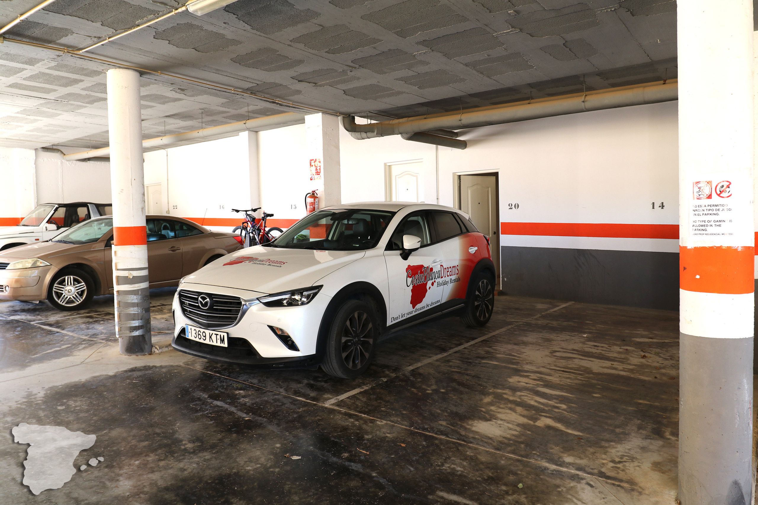 Un parking où une voiture blanche est garée sur une place marquée du numéro 20.