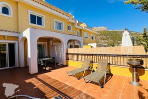 Un edificio amarillo con un patio que tiene dos sillones y una mesa.