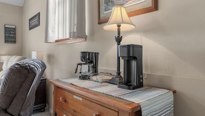 Une chambre d’hôtel avec un lit, un bureau doté d’une machine à café, une lampe, un tableau encadré au mur et un panneau affichant des citations inspirantes.