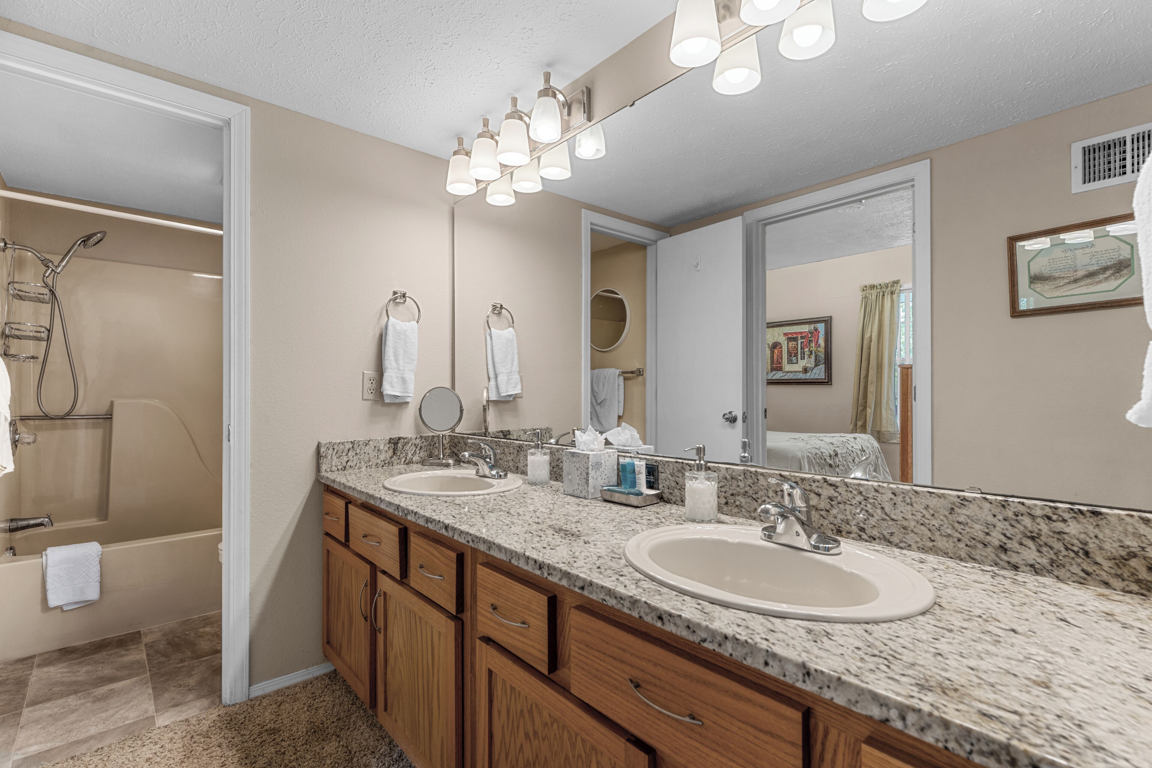 Une salle de bain avec un double lavabo, des meubles en bois, une douche et un grand miroir.