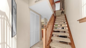 Un escalier avec une rampe en bois et des marches recouvertes de moquette, menant à un palier.