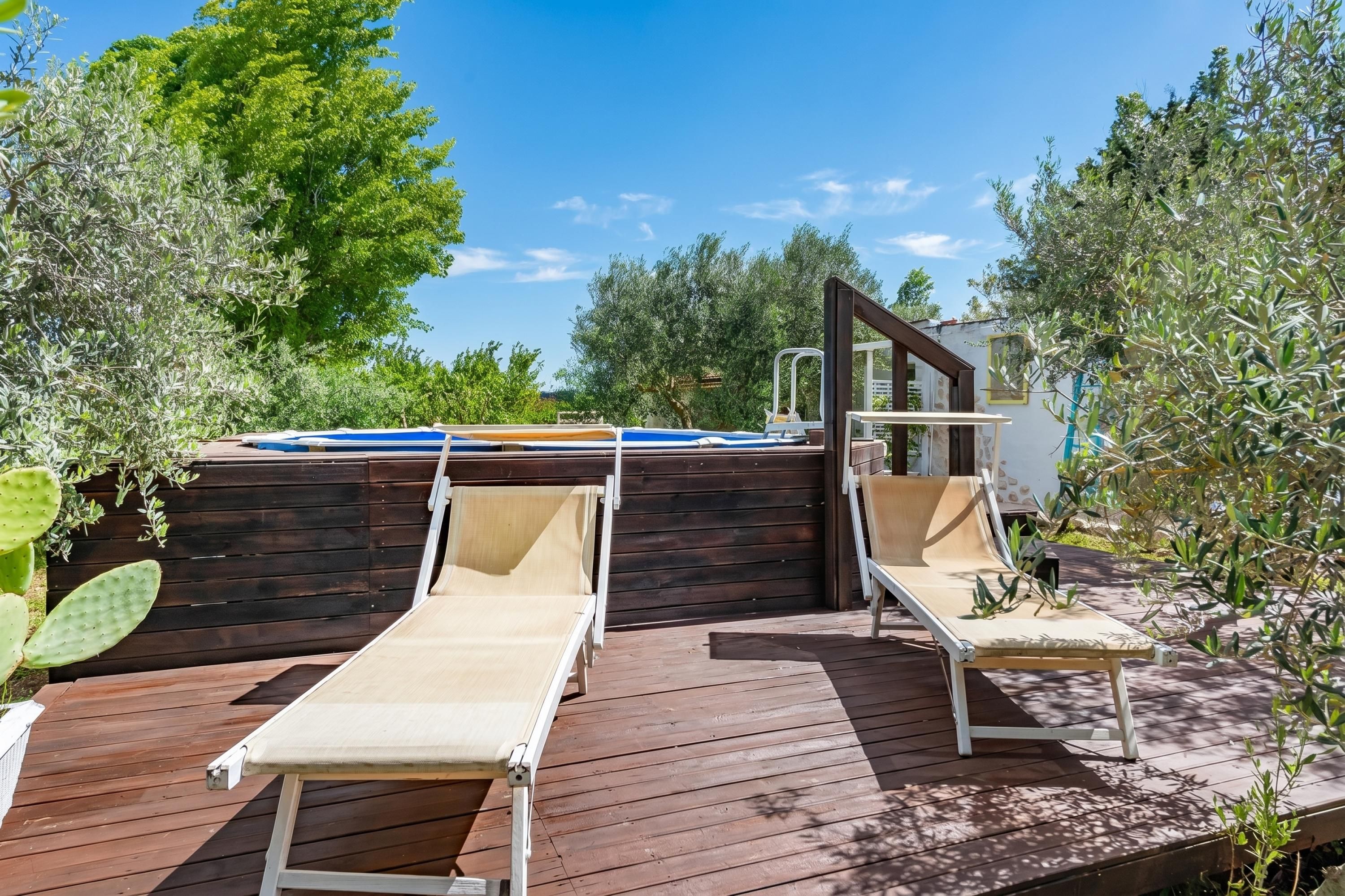 Eine Holzterrasse mit zwei Liegestühlen und einem Trampolin.