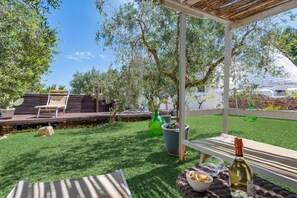 Une terrasse avec une table, des chaises et une bouteille de vin.