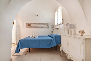 Een kamer met een bed, een dressoir, een raam en een kunstwerk aan de muur.