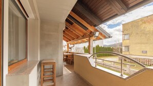 A balcony with a wooden railing, a concrete bench, and a view of a residential area with houses and trees. - House Dijana Pool & Garden (Bloke)