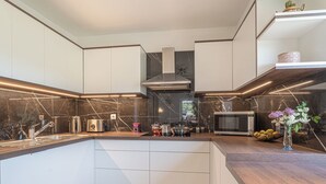 A modern kitchen with white cabinetry, a marble backsplash, and a wooden countertop. - House Dijana Pool & Garden (Bloke)