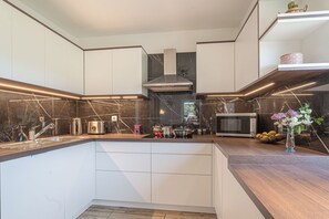 A modern kitchen with white cabinetry, a central island, and a microwave. - House Dijana With Pool (Bloke)