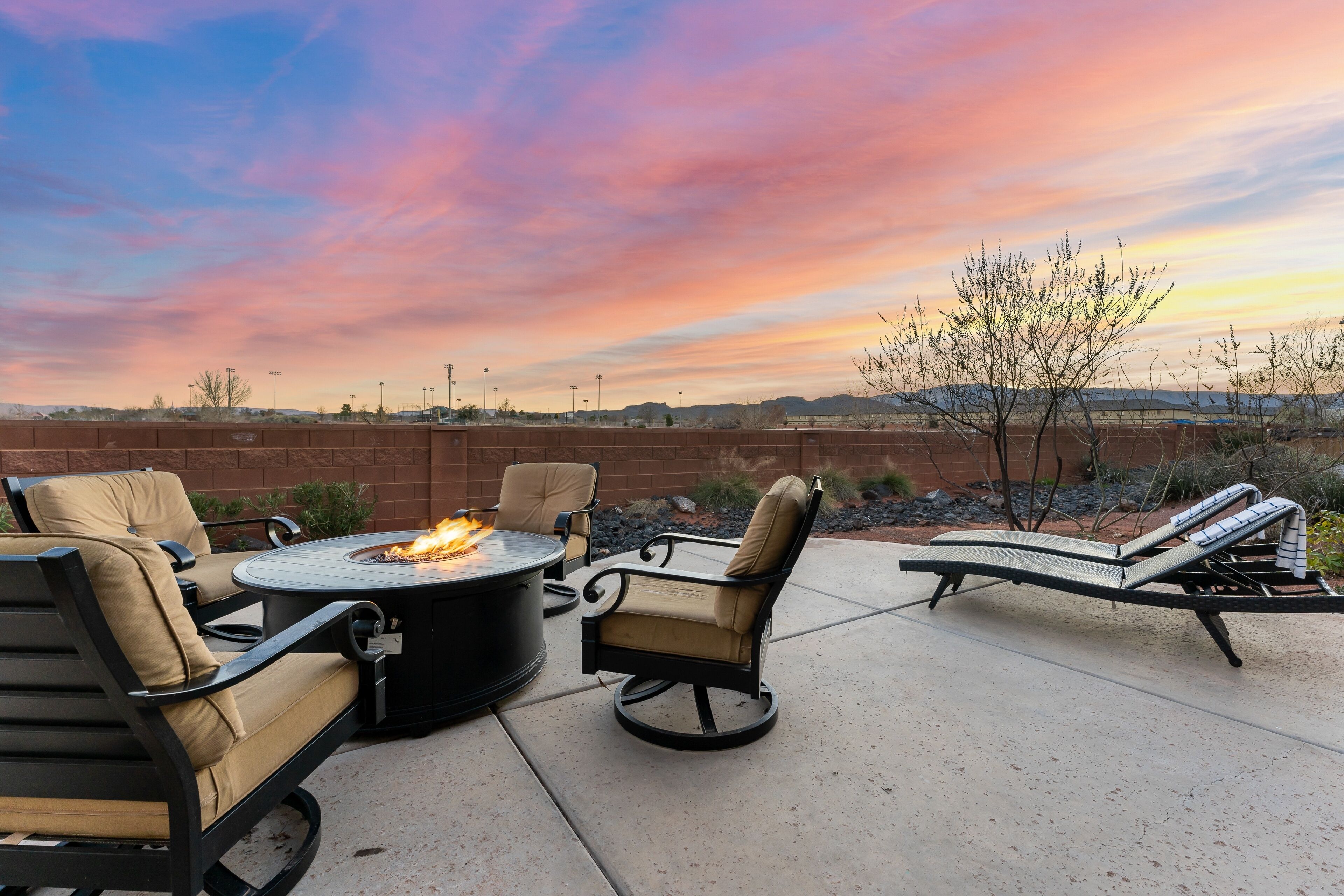 Une terrasse extérieure dotée d’un foyer, de chaises longues et offrant une vue sur le paysage.