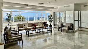 A spacious living room with a large window overlooking the ocean, a sofa, two armchairs, and a coffee table. - Luxury apartment on the beach (La Caleta)