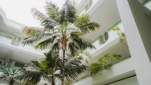 A multi-level atrium with a central palm tree, white walls, and green railings. - Luxury apartment on the beach (La Caleta)