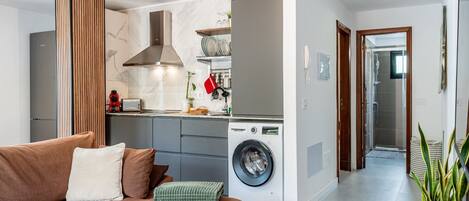 A modern kitchen with a built-in washing machine, grey cabinets, and a wooden accent wall.