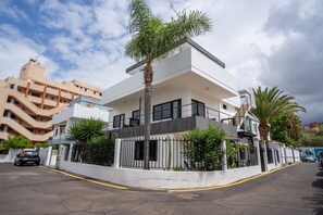 Un edificio moderno de dos pisos con techo plano, ventanas grandes y un balcón.