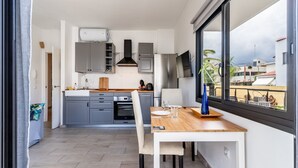 A modern kitchen with grey cabinets, a built-in oven, and a dining area with a table and chairs.