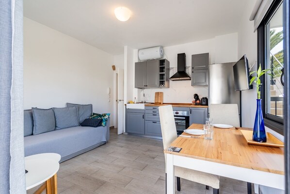 Un espacio habitable compacto con kitchenette, comedor y sofá.