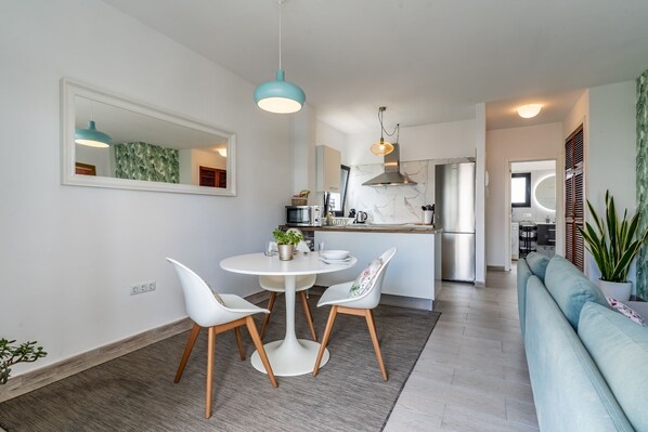 A modern kitchen with a central island, white chairs, and a dining table.