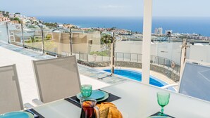 Una mesa de desayuno con platos, vasos y comida, con vistas a una ciudad costera.