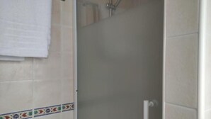 A bathroom with a shower, a towel hanging on the wall, and decorative tiles. - Estudio Premium Sierra Nevada (Sierra Nevada)