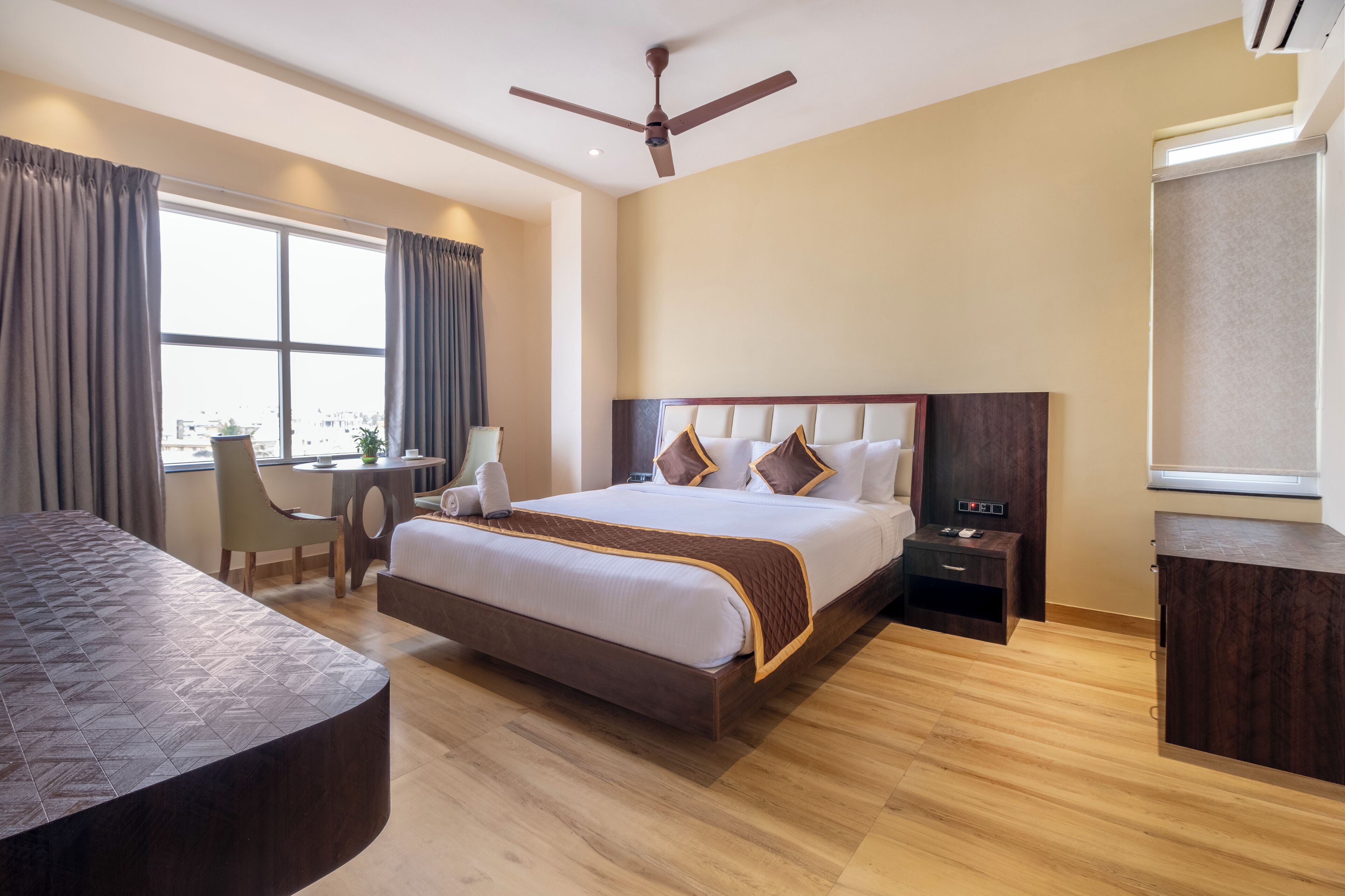 A modern hotel room with a large bed, a desk, and a chair.