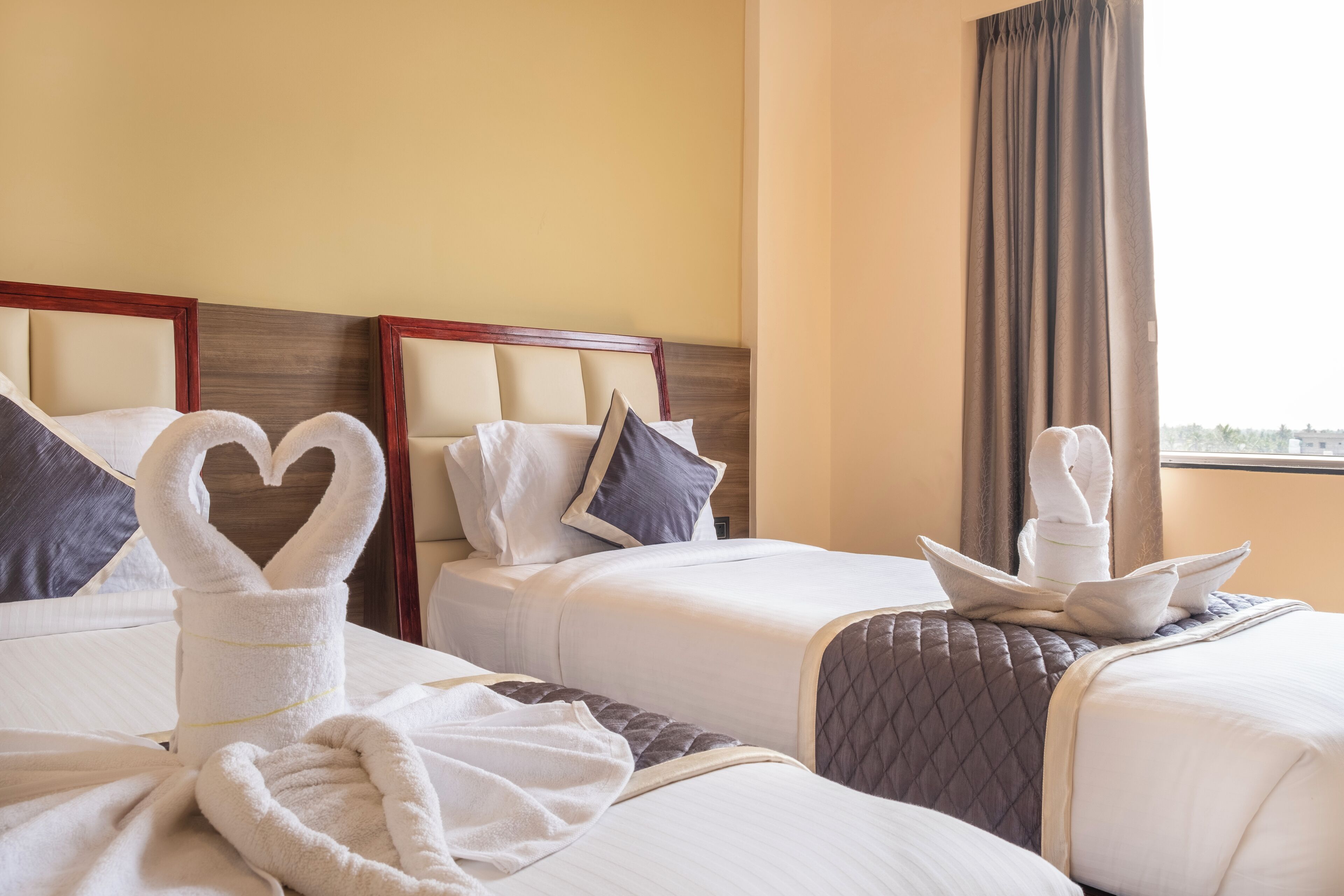 A hotel room with two beds, each with a heart-shaped towel arrangement.