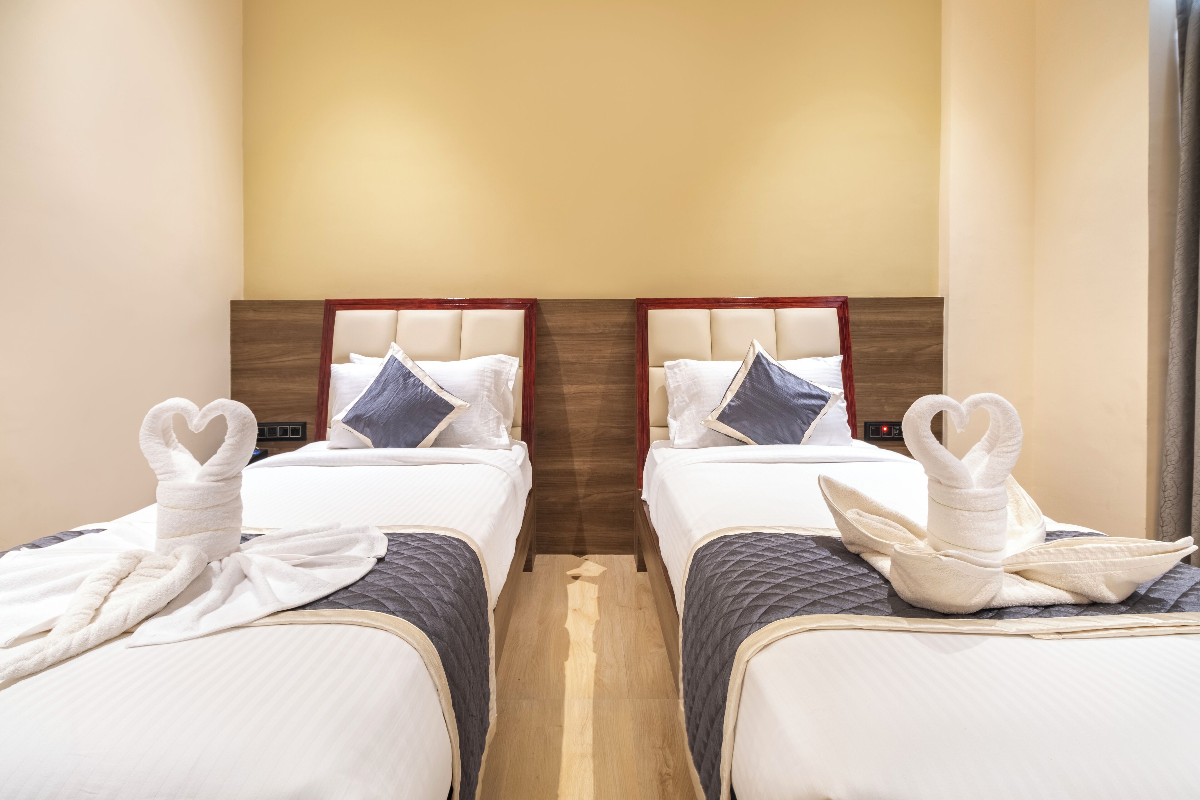 Una habitación de hotel con dos camas, cada una con una toalla con forma de corazón y una almohada.