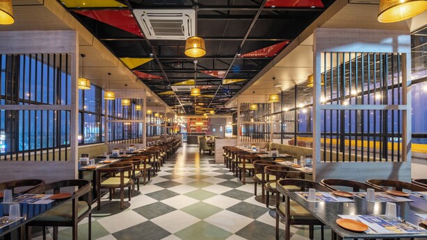 Restaurante com chão xadrez, várias mesas e cadeiras.