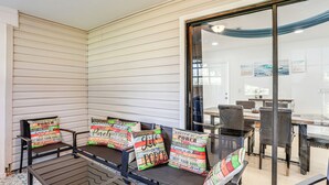 Een overdekt terras met een eethoek, inclusief een tafel, stoelen en decoratieve kussens met tekst.
