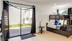 Een kamer met een stapelbed, een bureau met een lamp en een glazen schuifdeur die uitkomt op een terras.