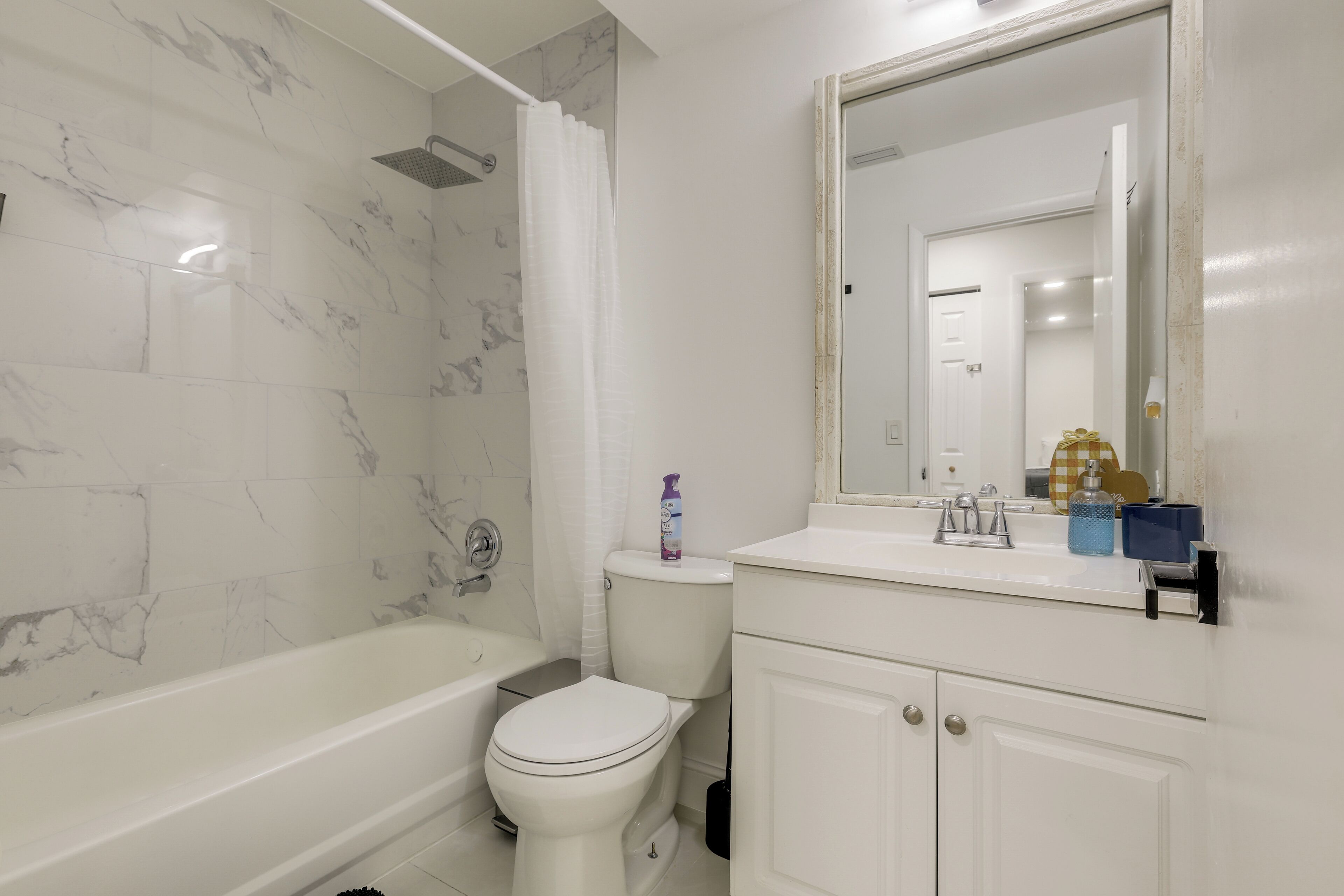 Un baño con bañera, inodoro y tocador con espejo.