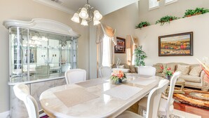A dining area with a marble table, white chairs, a glass cabinet, and a chandelier.
