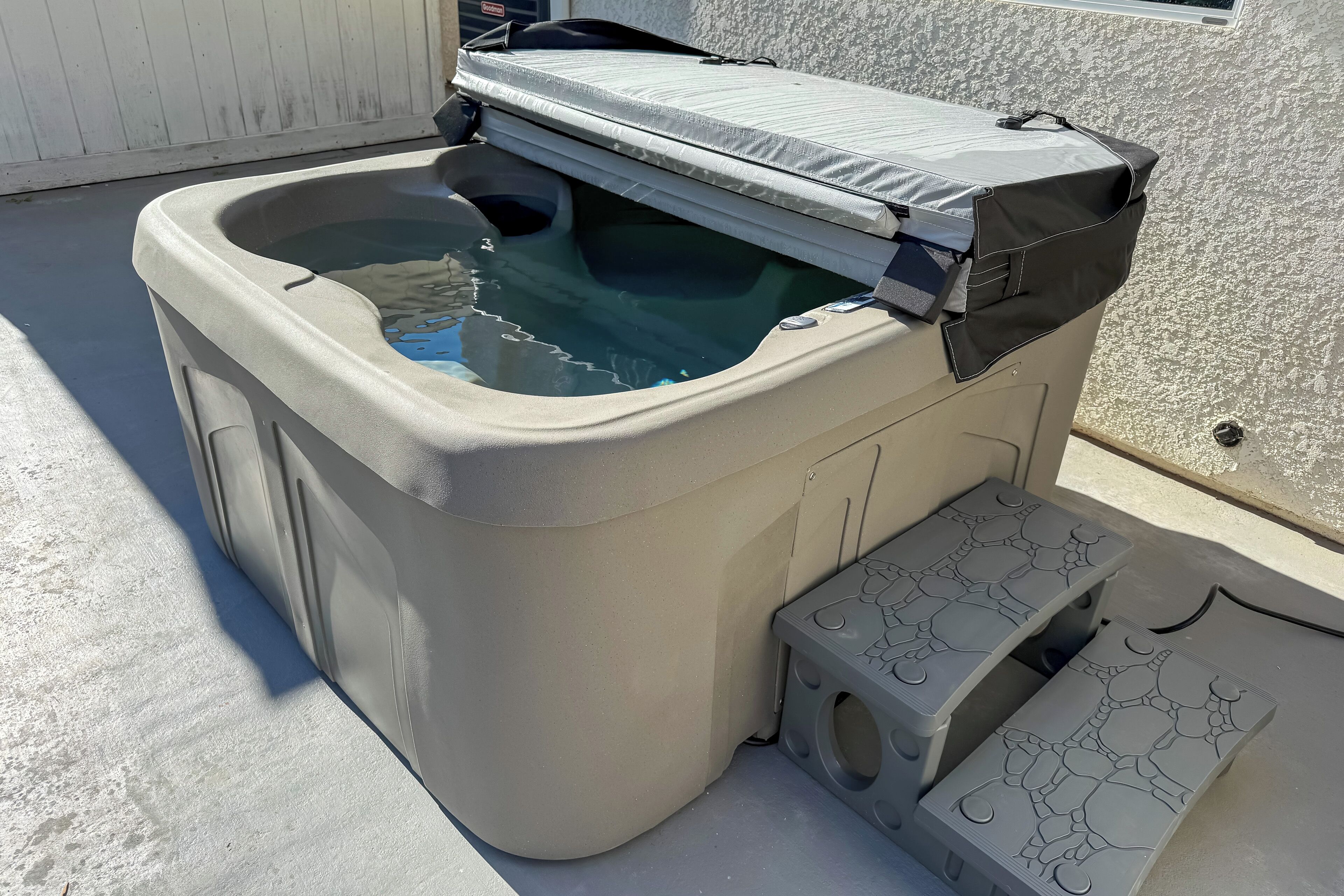 A hot tub with a cover, steps, and a small pool.