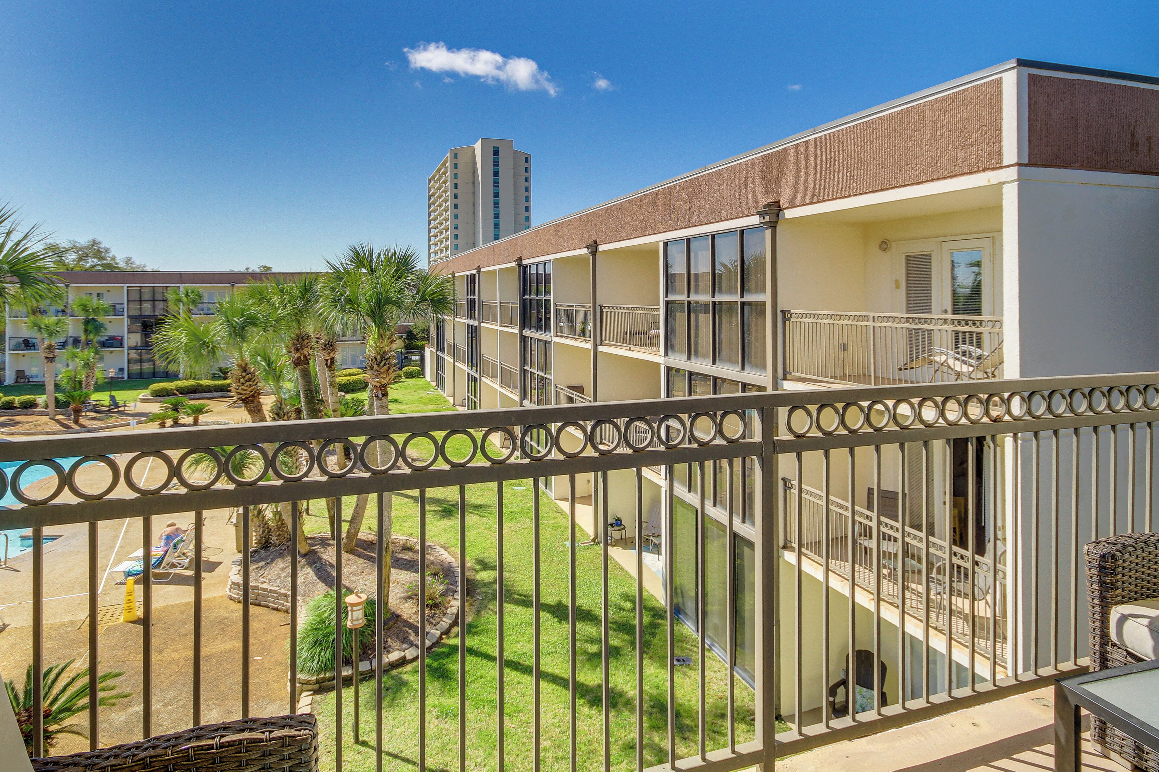 Un hôtel à plusieurs étages doté de balcons, d’un espace piscine et de palmiers.