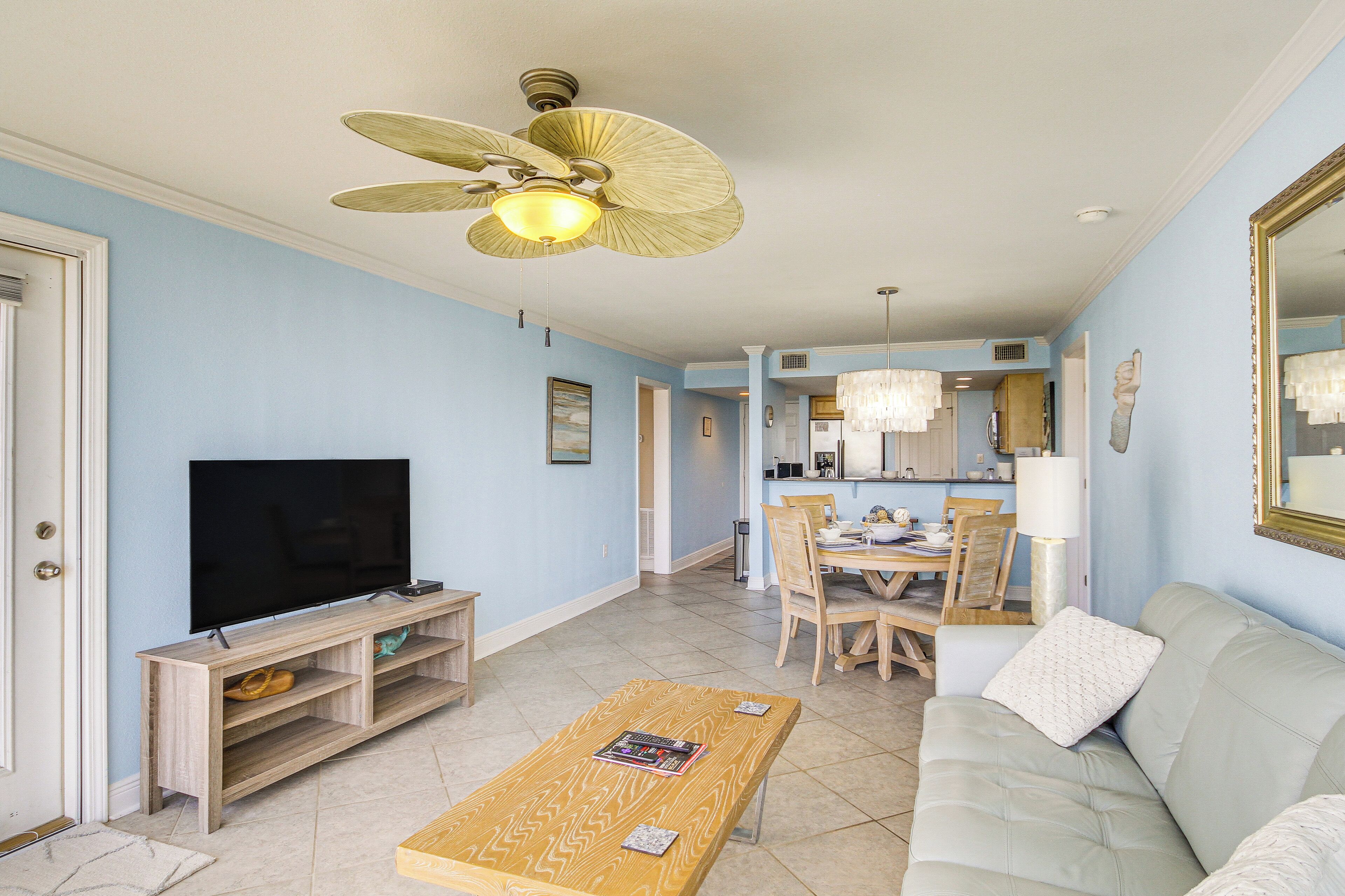 A living room with a television, wooden entertainment unit, and a ceiling fan.