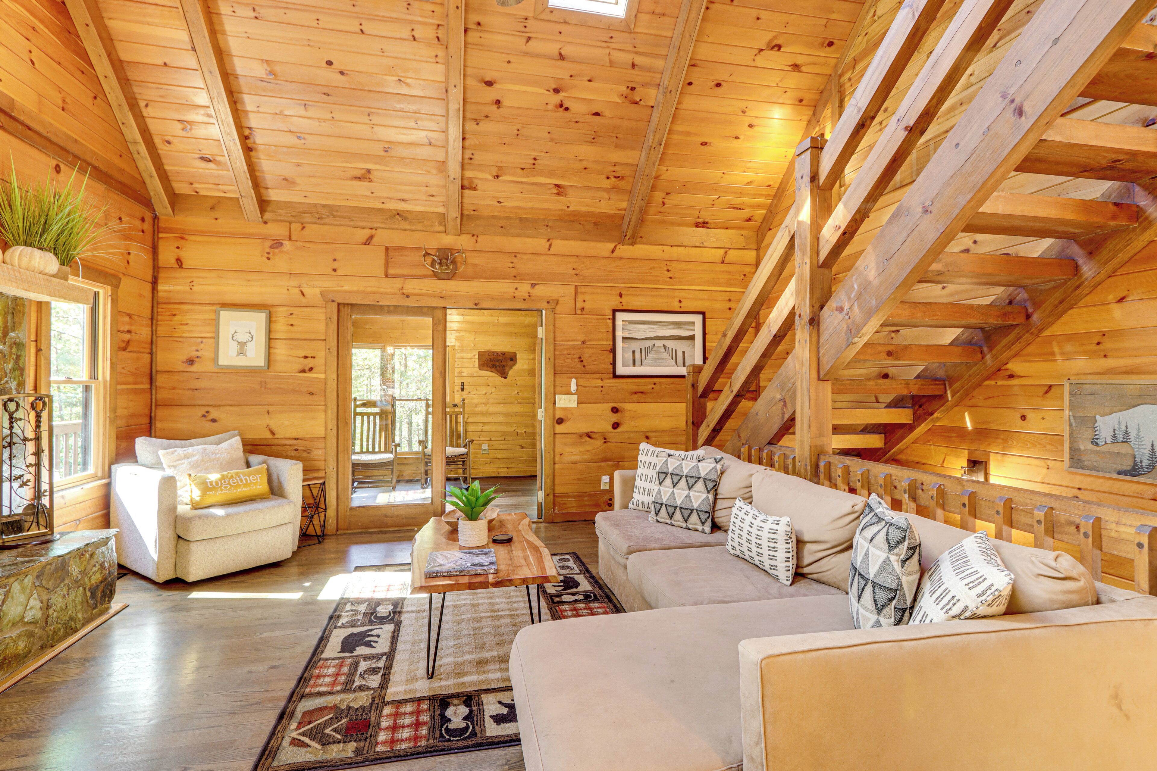 A log cabin interior with a sofa, coffee table, and a staircase.