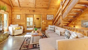 A cozy log cabin interior with a wooden ceiling, a sofa set, a coffee table, and a staircase. - Blue Ridge Cabin w/ Hot Tub, Fire Pit, & Game Room (Cherry Log)