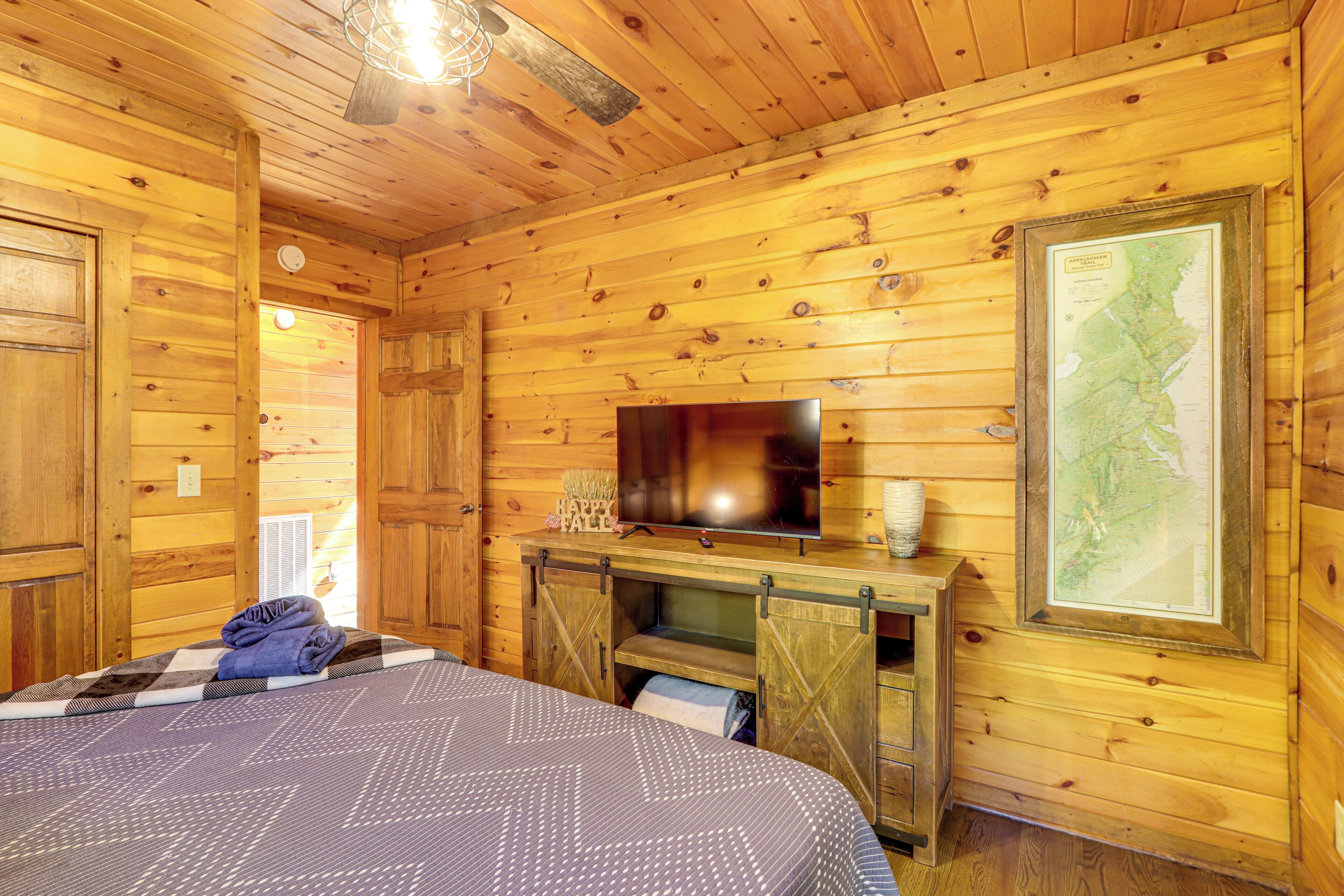 A wooden cabin room with a bed, a television, and a map on the wall.