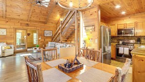 A wooden cabin interior with a dining area, kitchen, and living space. - Blue Ridge Cabin w/ Hot Tub, Fire Pit, & Game Room (Cherry Log)