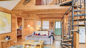 A cozy log cabin interior with a living room, a staircase, and a kitchen area. - Lamoine Cabin w/ Deck ~ 16 Mi to Acadia Natl Park (Ellsworth)