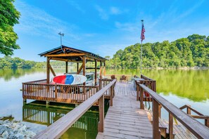 A wooden dock extending into calm water with a covered seating area and a flag. - 'duck and Bug's Cabin' on Boone Lake w/ Boat Dock! (Piney Flats)