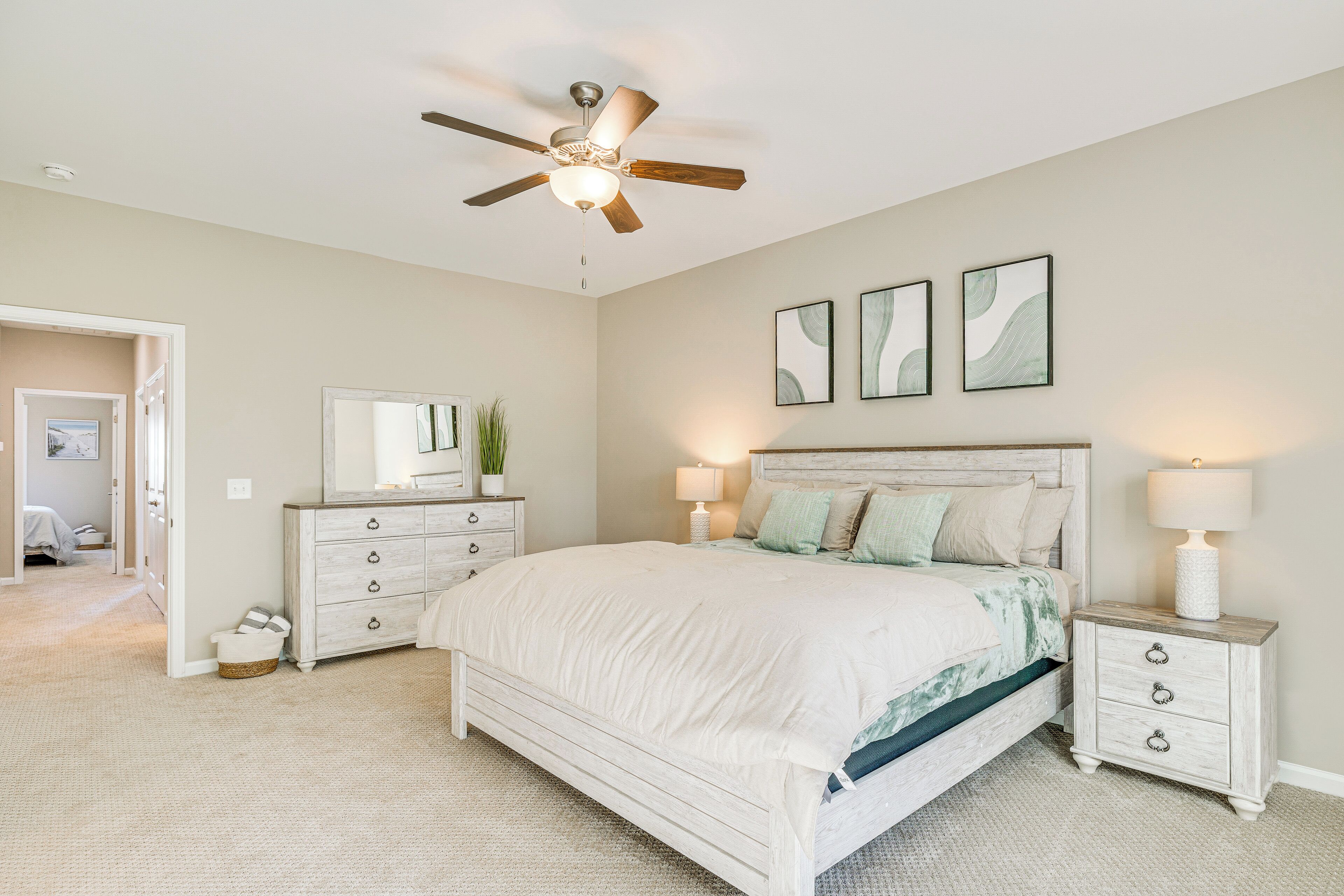 A bedroom with a bed, nightstands, a ceiling fan, and wall art.