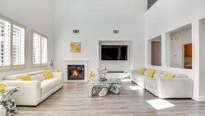 A spacious living room with a fireplace, two white sofas with yellow cushions, and a glass coffee table. - 4 Mi to Dtwn Merced: Spacious Home w/ Yard! (Merced)