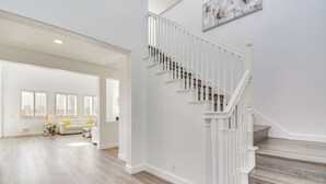 A spacious living area with a wooden floor, a white staircase, and a dining area in the background. - 4 Mi to Dtwn Merced: Spacious Home w/ Yard! (Merced)