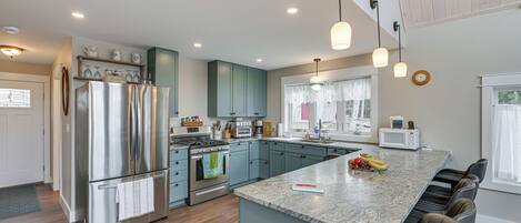 A modern kitchen with a large island, stainless steel appliances, and a breakfast bar.